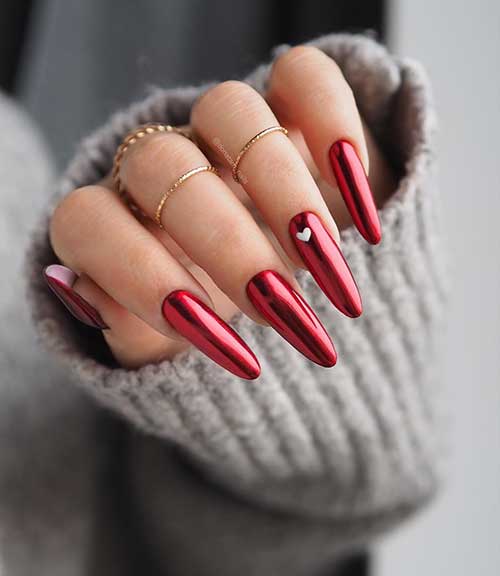 Gorgeous mirror red Valentine’s Day nails almond shaped with a tiny white heart on the ring fingernail