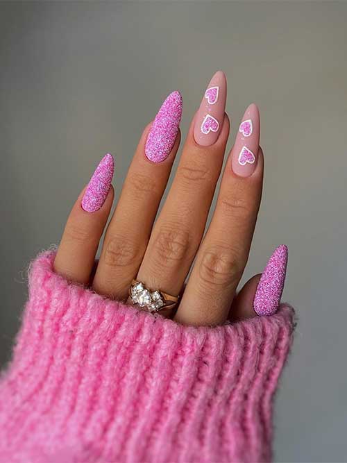 Hot pink Valentine's Day nails with sugar glitter and two accent matte nude nails adorned with two glittery hot pink hearts