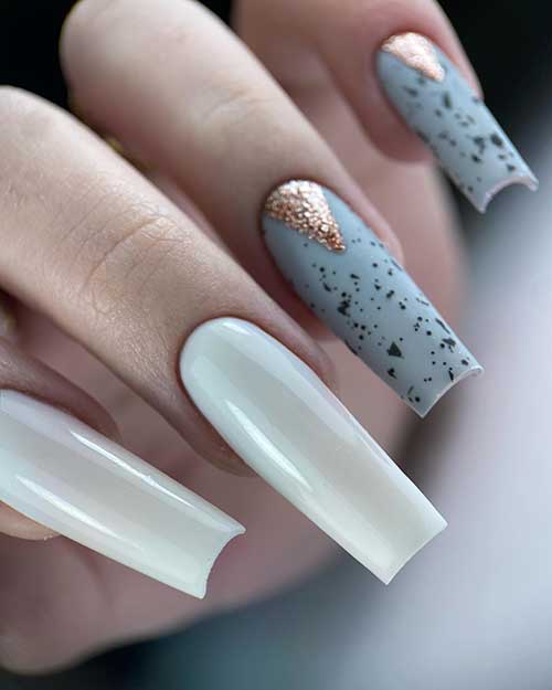 Long grey and white nail design features matte light grey nails with black speckles and two accent glossy solid white nails
