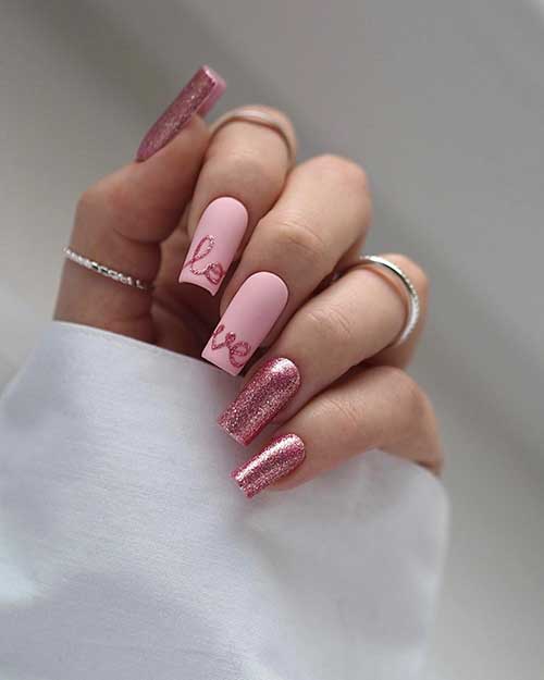 Long square-shaped sparkling Valentine’s nails feature pink glitter nails with two accent matte pink nails with the LOVE word