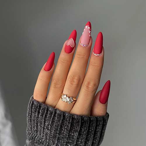 Matte long red Valentine’s Day nails adorned with rhinestones on two accent nails besides heart nail art designs