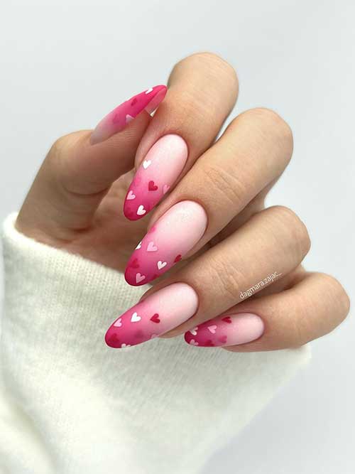 Matte ombre hot pink Valentine's Day nails with a touch of glitter adorned with white, pink, and red heart shapes Matte ombre hot pink Valentine's Day nails with a touch of glitter adorned with white, pink, and red heart shapes