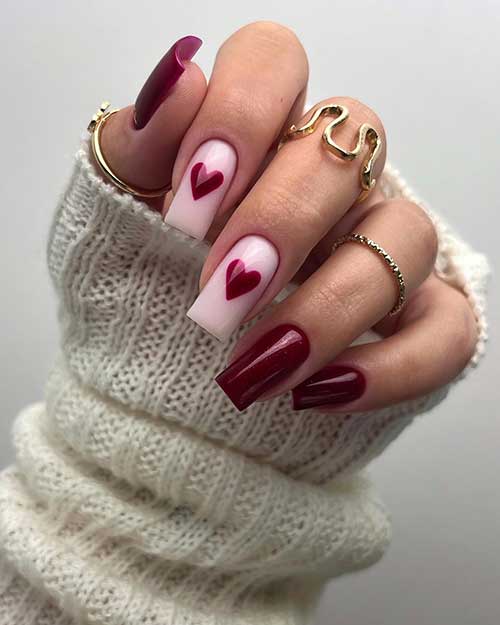 Shimmer Dark red Valentine’s Day nails with two accent pastel pink nails adorned with a big dark red heart