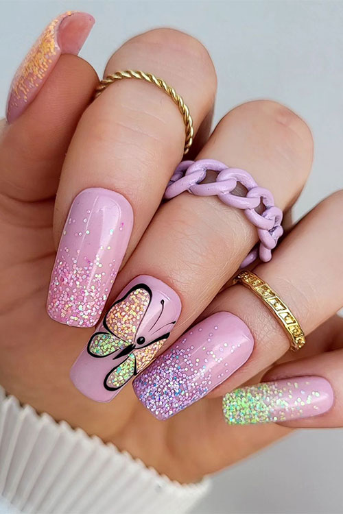 Cute long multicolored glitter ombre nails over a nude pink base color and a gold and green butterfly nail art design