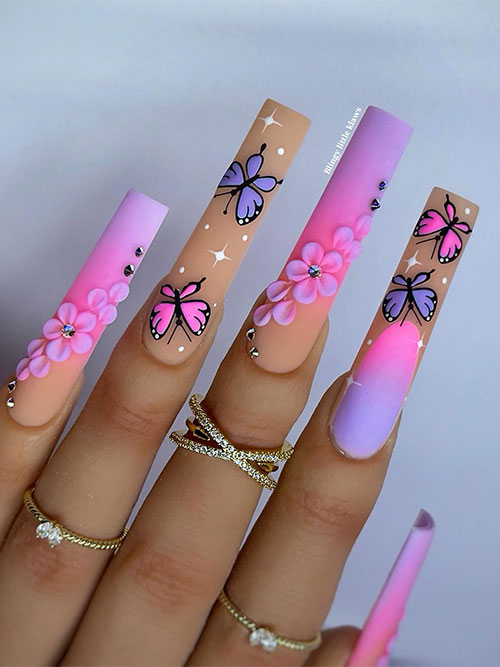 Long matte pink and purple ombre butterfly nails with prominent floral nail art on two accents adorned with rhinestones