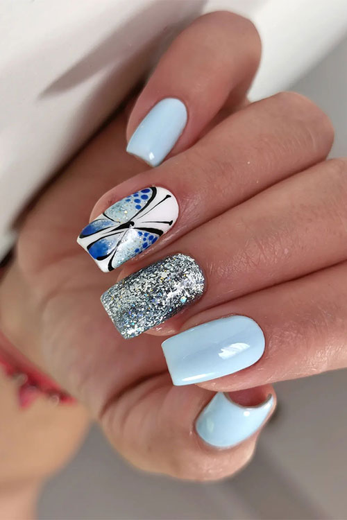 Medium square-shaped light blue nails with a butterfly design on an accent nail besides, a silver glitter accent nail