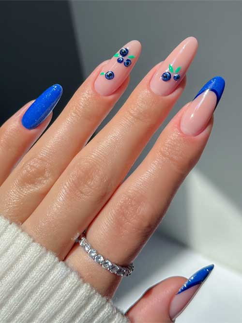 Blueberry-inspired nail art features nude and blue hues, with whimsical blueberries and royal blue French tips for a chic look. Blueberry-inspired nail art features nude and blue hues, with whimsical blueberries and royal blue French tips for a chic look.