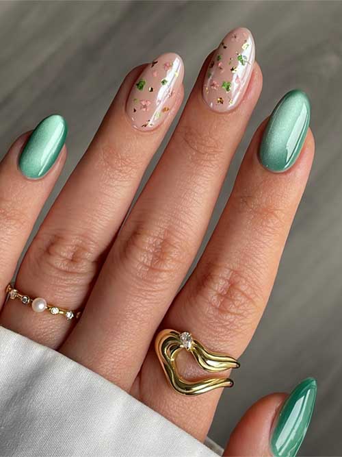 Elegant green cat eye spring nails with pink floral accents, almond shape, and gold rings with pearls and diamonds. Elegant green cat eye spring nails with pink floral accents, almond shape, and gold rings with pearls and diamonds.