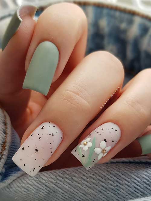 Elegant green spring nails featuring matte and speckled white accents, with floral details on the ring finger for a seasonal touch. Elegant green spring nails featuring matte and speckled white accents, with floral details on the ring finger for a seasonal touch.