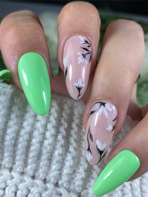 Elegant green spring nails with glossy green, nude, and white floral patterns, featuring almond shapes and black vines. Elegant green spring nails with glossy green, nude, and white floral patterns, featuring almond shapes and black vines.