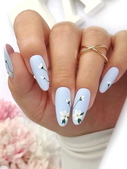 Elegant powder blue matte nails adorned with soft white blossoms, evoking a peaceful garden vibe for your manicure. Elegant powder blue matte nails adorned with soft white blossoms, evoking a peaceful garden vibe for your manicure.