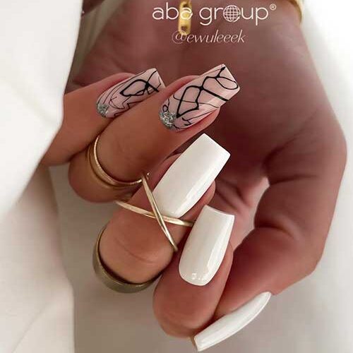 Minimalist white nails with pink accents and abstract black lines, finished with silver glitter for a stylish and elegant touch.