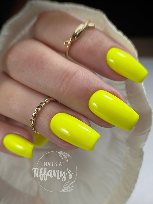 Bold neon yellow coffin nails offer a glamorous twist, perfect for stylish occasions and complementing gold accessories.