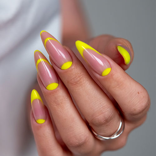 Modern and simple neon yellow nails featuring almond nails with a soft nude base and bright neon yellow tips.