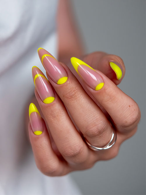 Modern and simple neon yellow nails featuring almond nails with a soft nude base and bright neon yellow tips.